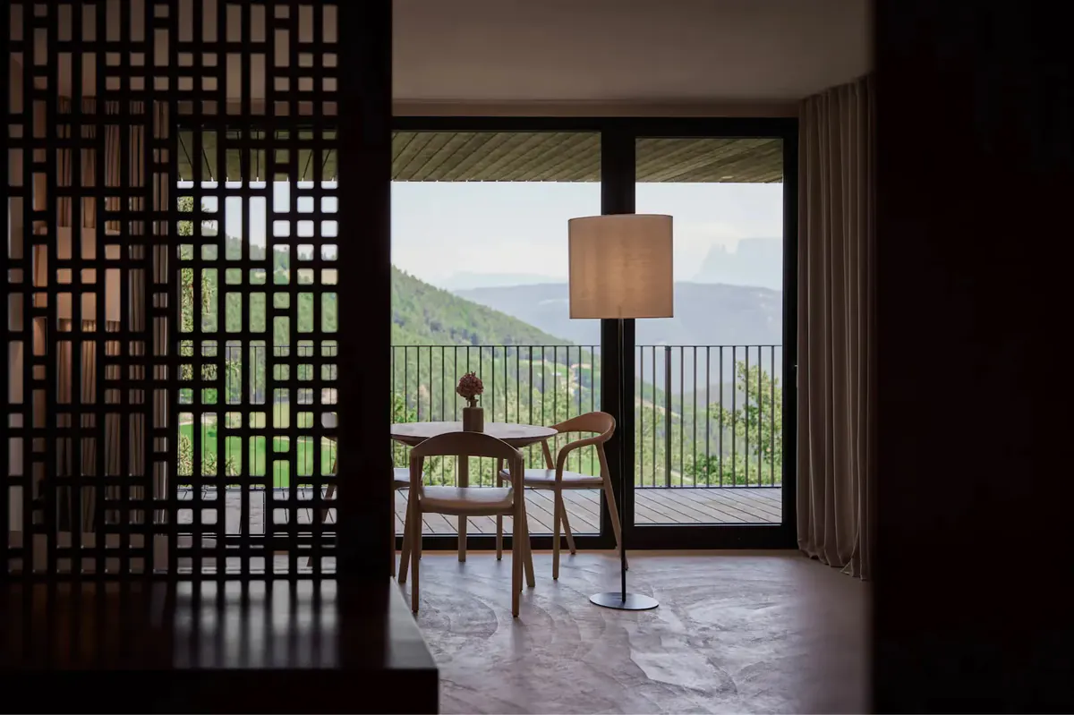 Dining area with geometric wooden screen partition and mountain view through glass doors