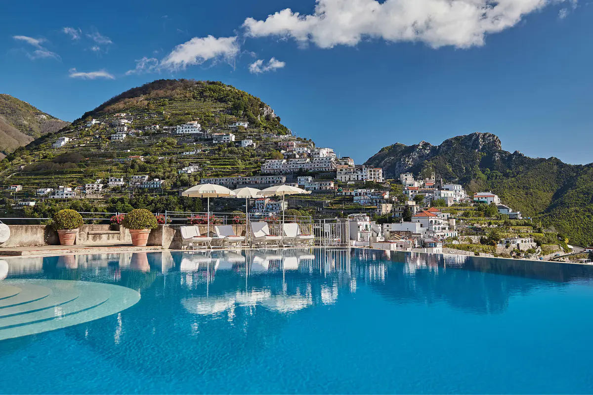 Aerial view of infinity pool on hillside village with turquoise water and coastal landscape