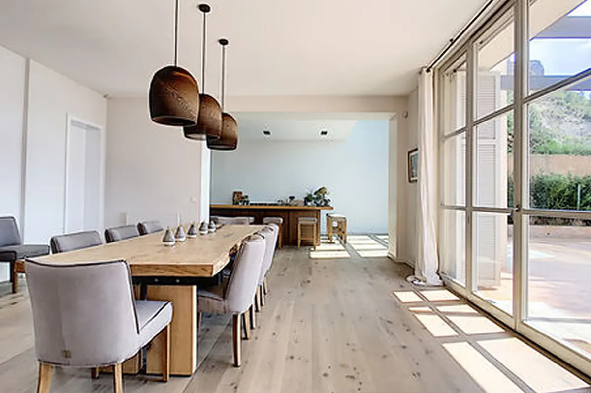 Contemporary dining space with natural wood table, modern pendant lights, and expansive windows