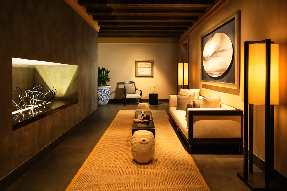 Spa corridor with warm wood tones, sconces, and treatment rooms in ambient lighting
