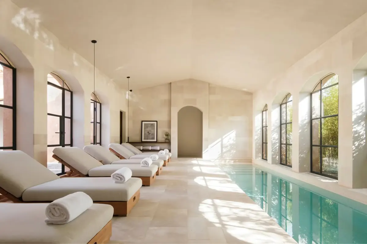 Indoor pool with loungers and bright natural light from large windows