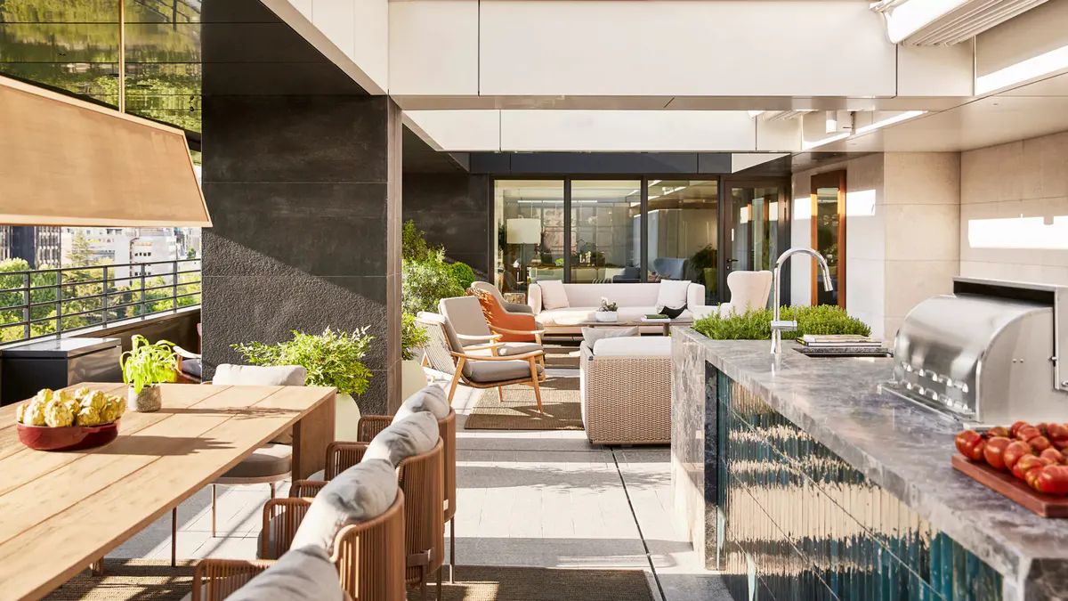 An outdoor terrace with modern furniture, shade structure, and views into the hotel interior