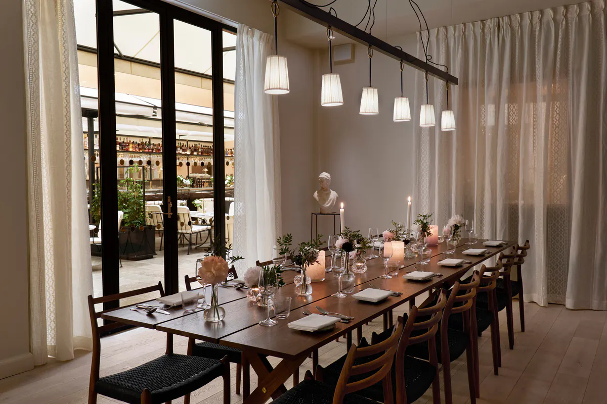 Private dining room with dark wood table, place settings, and floor-to-ceiling windows