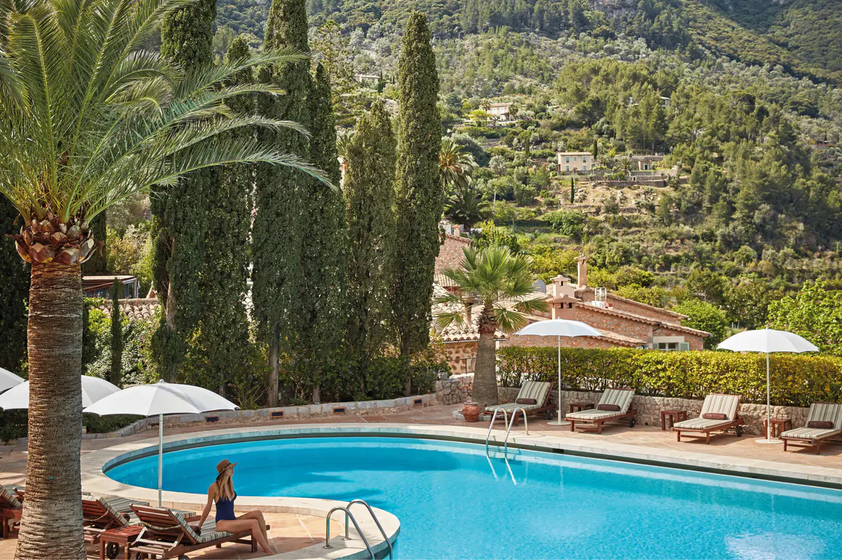Resort pool with lounge chairs and umbrellas overlooking Mediterranean countryside