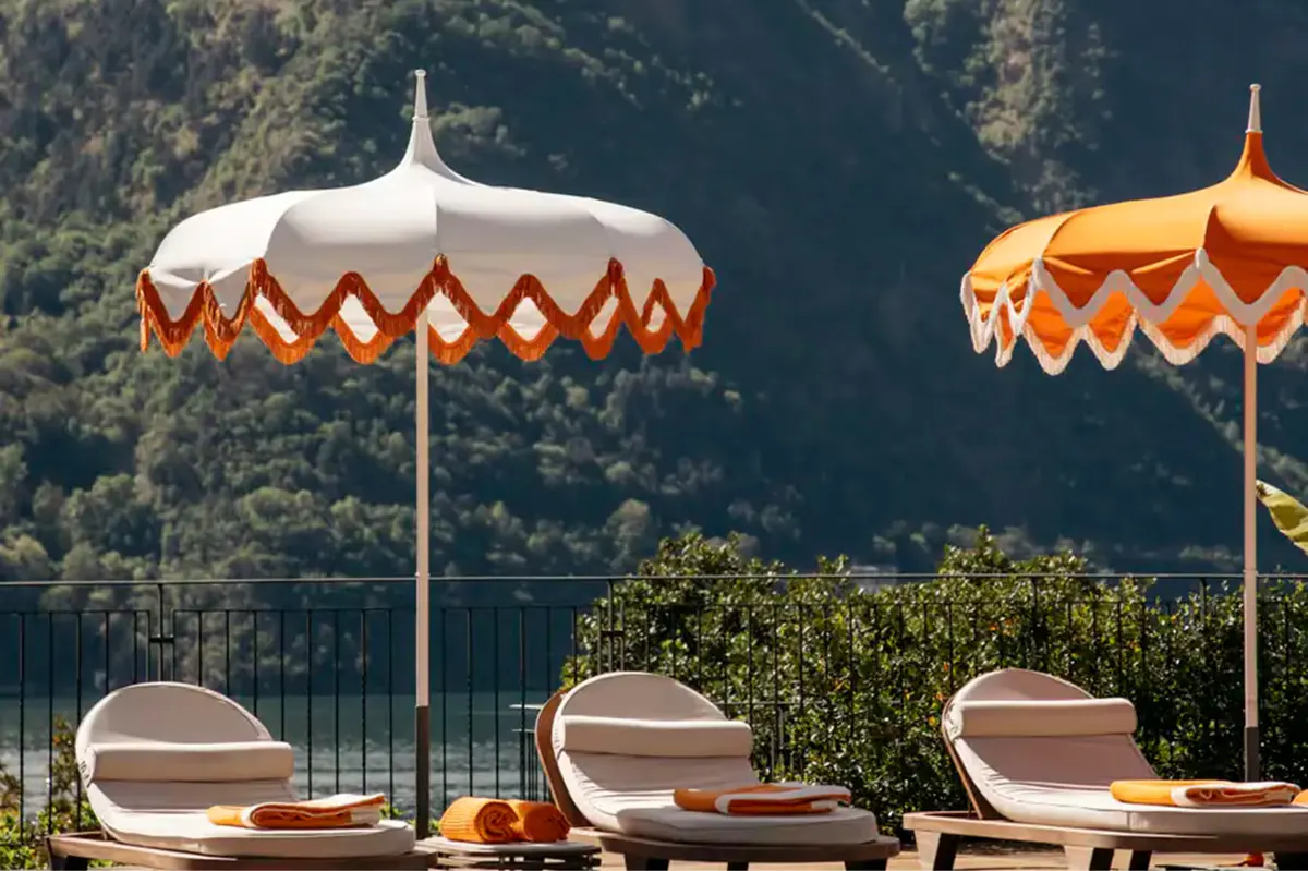 Loungers beneath striped umbrellas with lake and mountain views