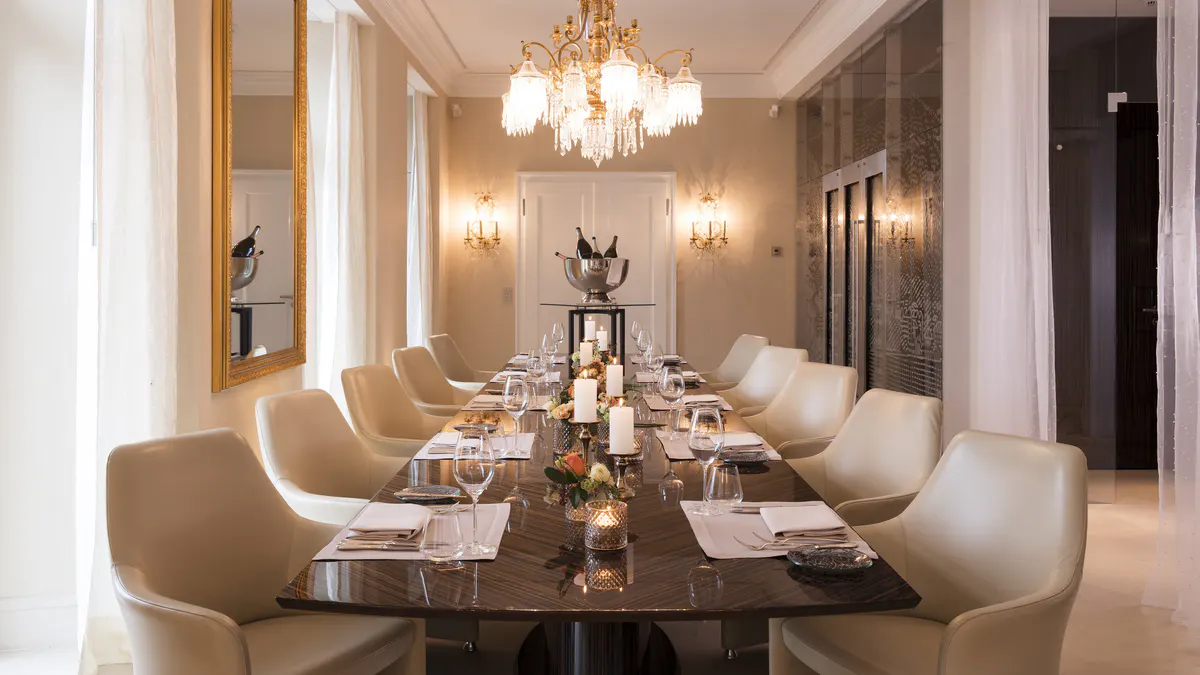 Formal dining room with crystal chandelier and beige upholstered chairs