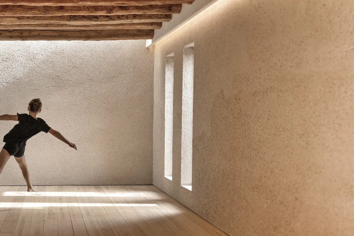 Movement or dance studio with soaring wooden ceiling, bright sidelighting, and person in mid-motion