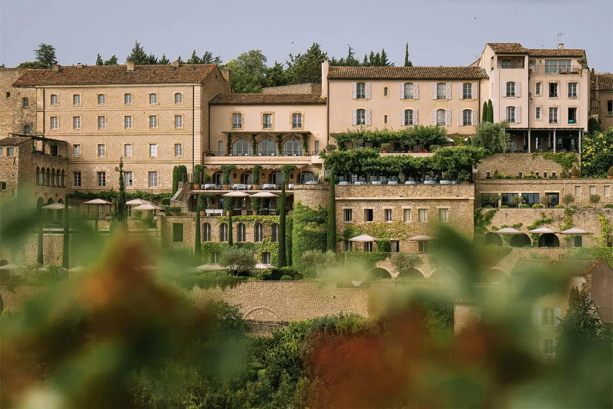 The honey stone facade of the hotel rising from terraced gardens