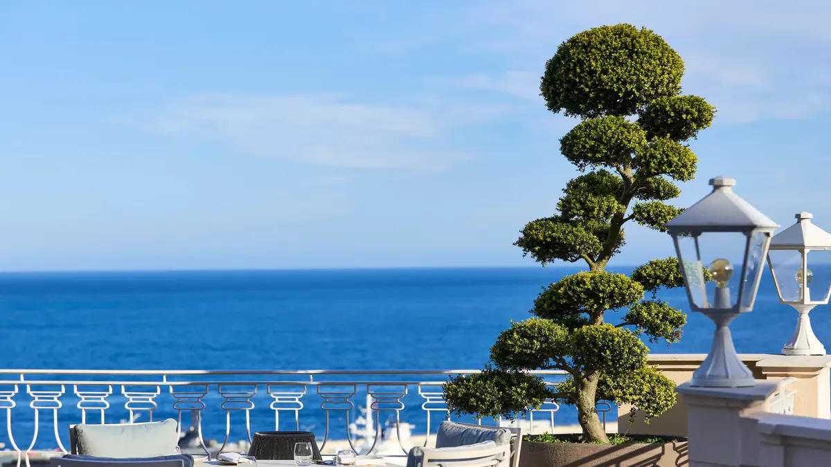 Seaside terrace with potted topiary and sweeping Mediterranean coastline