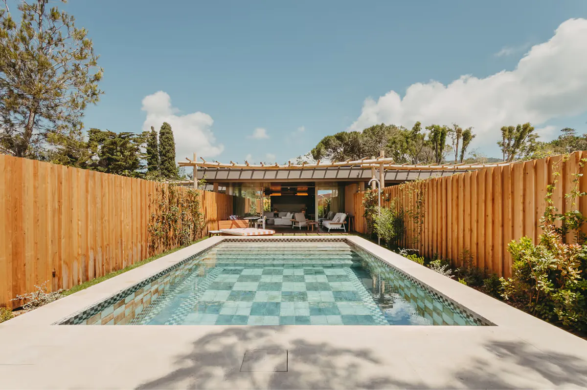 Pool with turquoise water tile pattern framed by wooden pergola