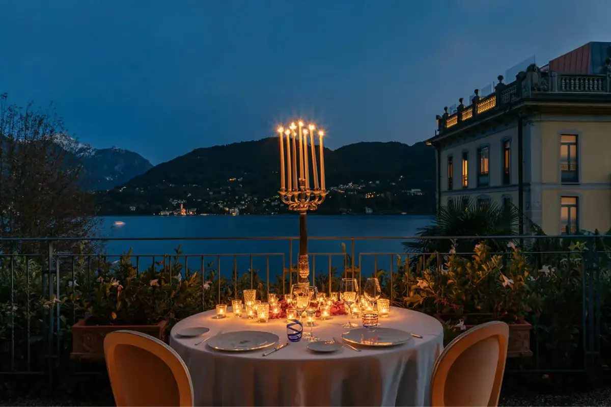Elegant outdoor dinner table at dusk with lakeside light and mountains