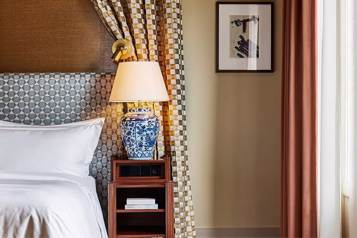Bed with upholstered headboard, layered bedding, and bedside tables with lamps