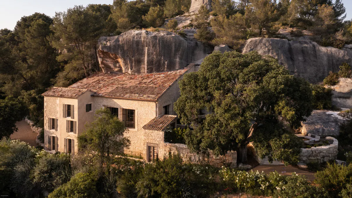 Stone villa set among cypress and olive trees amid soaring limestone rock formations, forested hillside