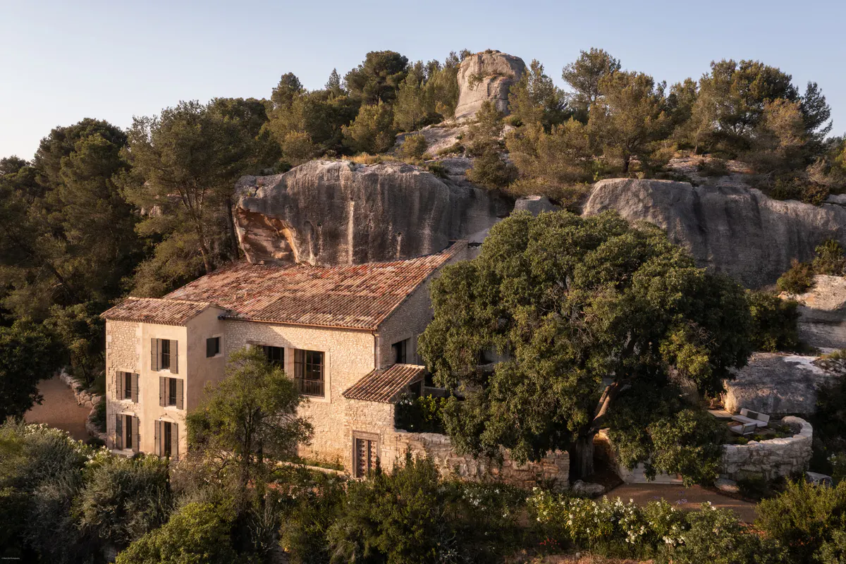 Stone villa with clay-tile roof set among conifers and limestone cliffs