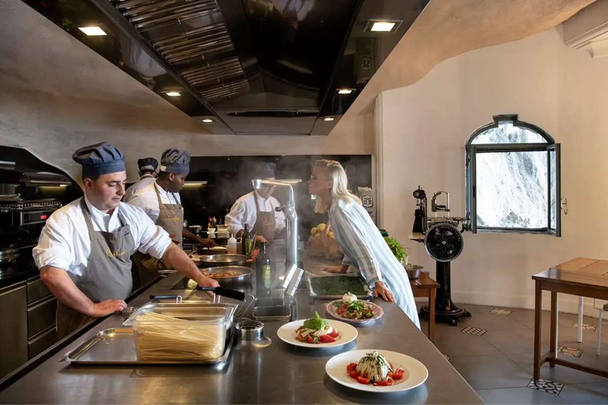 Open kitchen with chefs in white, plated dishes on counter, and warm interior lighting