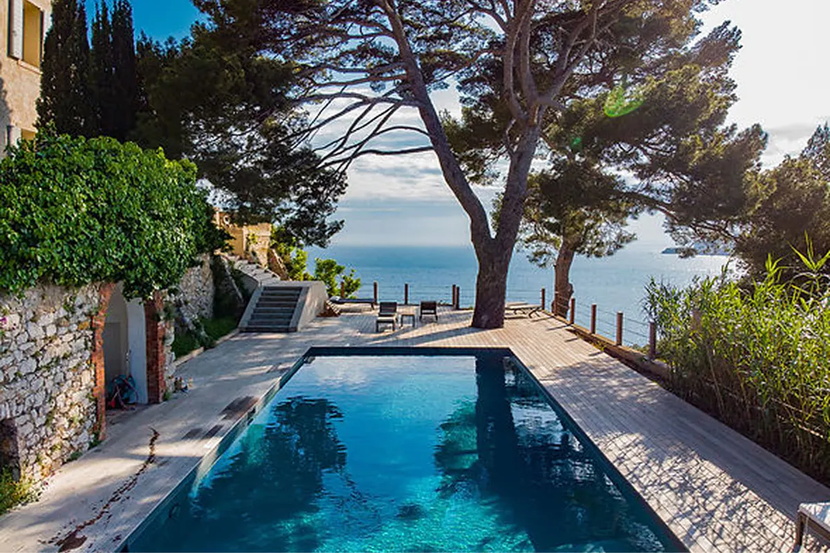 Infinity pool with sea view, Mediterranean pines, and coastal landscape at golden hour