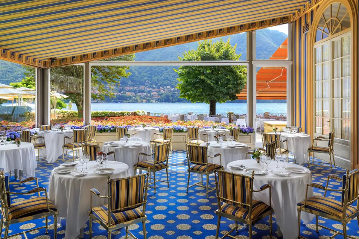 Formal dining room with white linens, striped chairs, and views of formal gardens