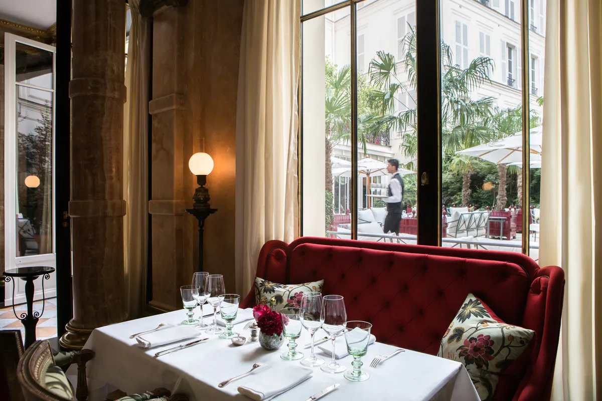 A restaurant window table with cream drapery and garden views