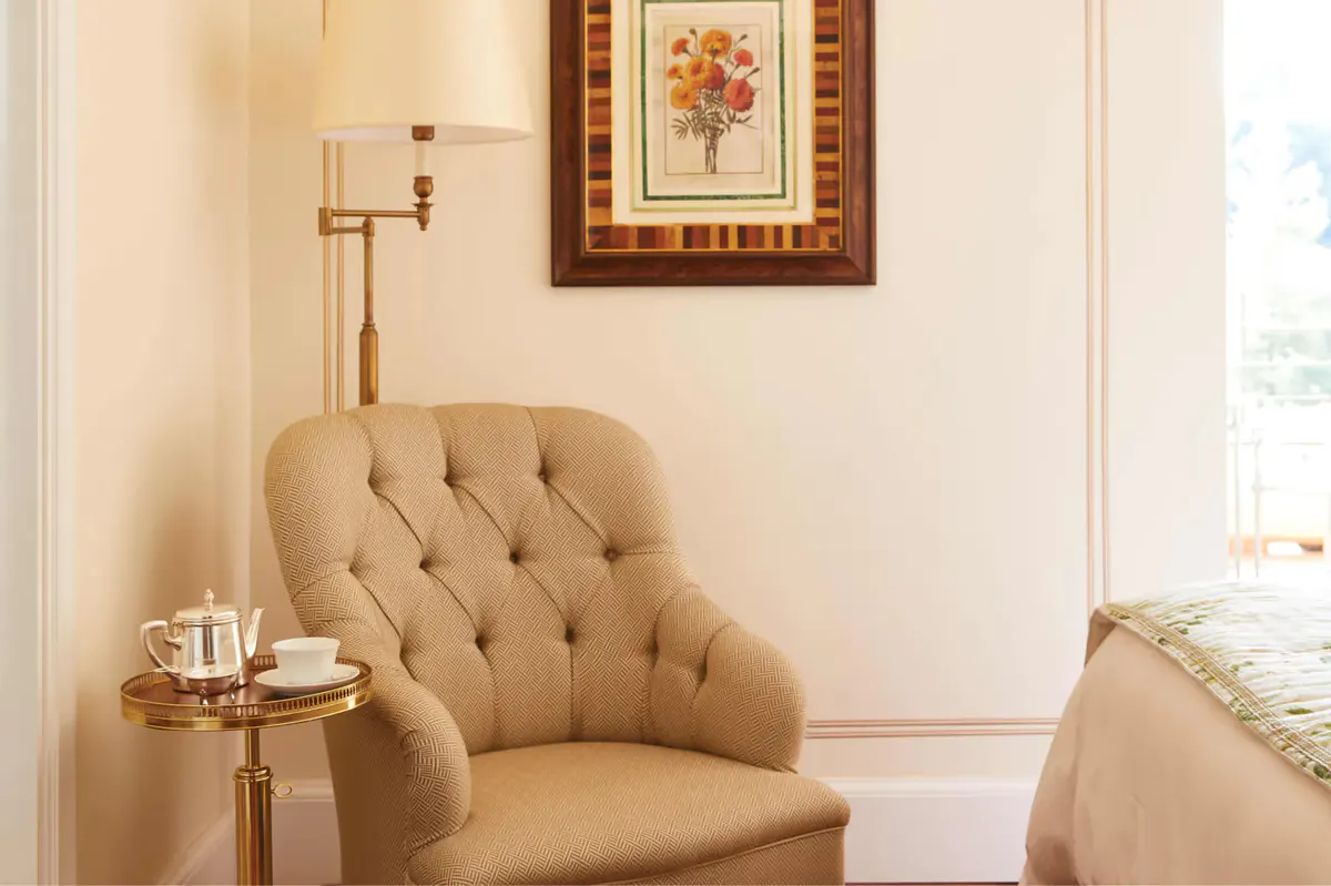 A sitting area with green velvet sofa, floral cushions, and botanical wallpaper