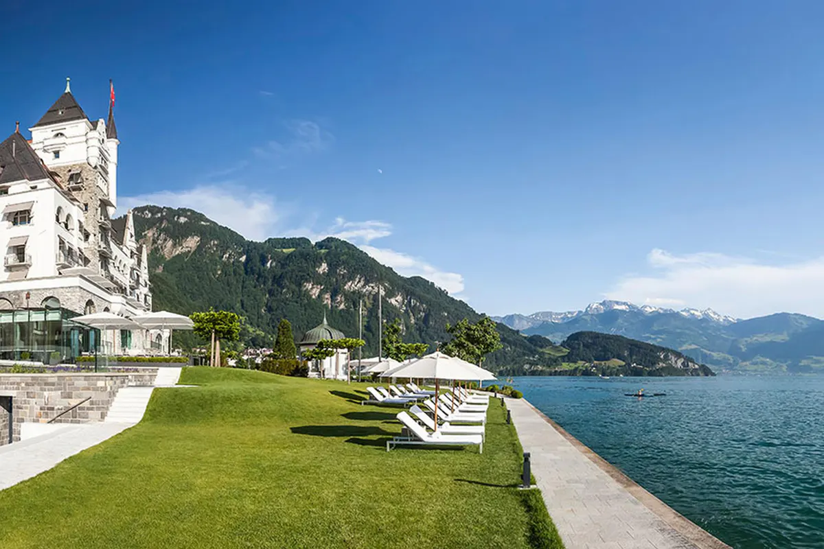 Manicured lawn beside the hotel with white lounge chairs overlooking the lake