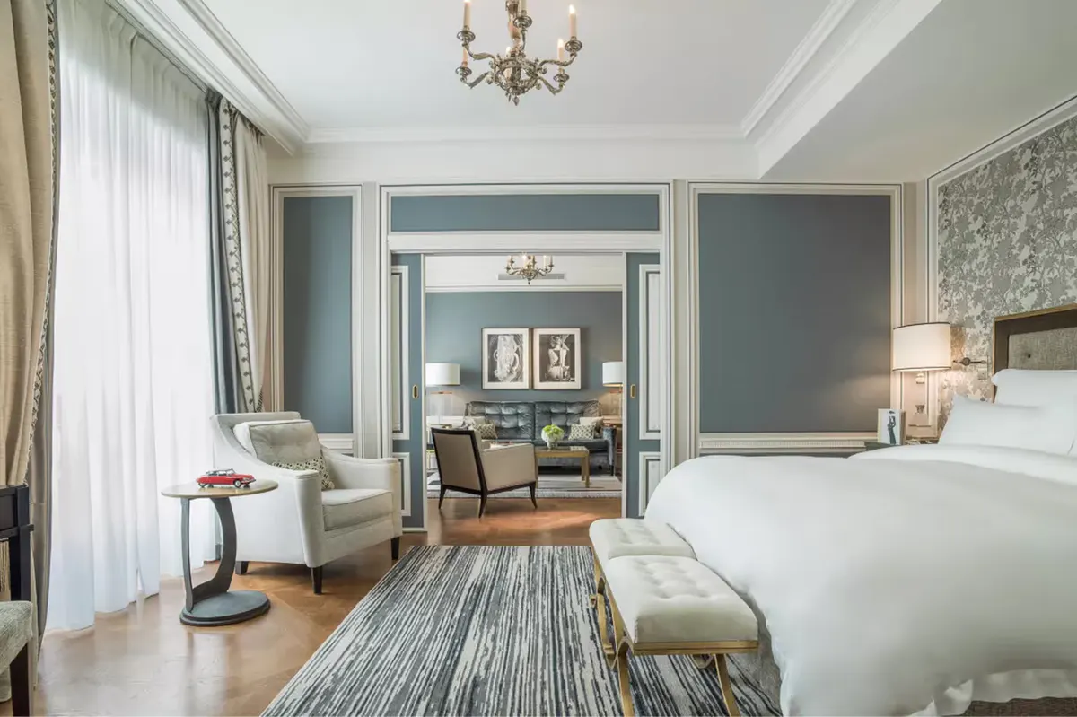 Generous bedroom with blue accents, crown ceiling, and multiple seating areas