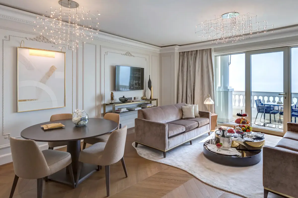 Suite living area in soft neutrals with round dining table and sea view