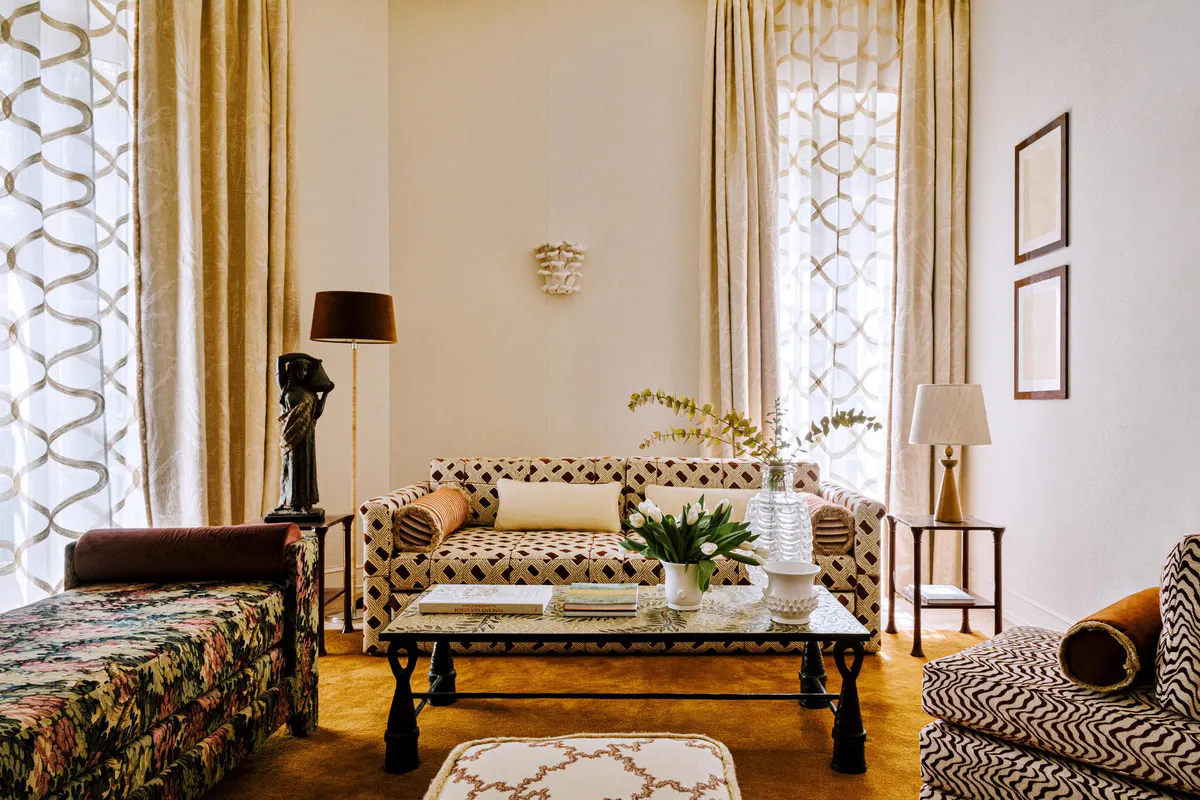 Suite sitting area with geometric patterned sofa, tall window with garden light, parquet flooring