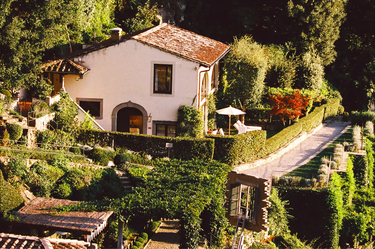 Aerial view of a villa building with terracotta roof, arched windows, and surrounded by manicured gardens