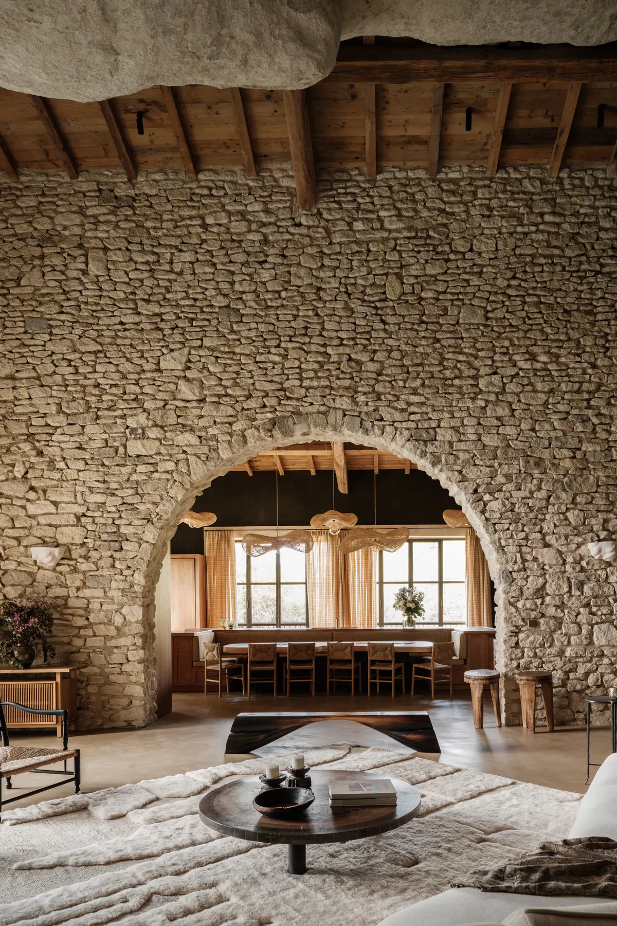 Stone archway with wooden lintels, dining room glimpsed beyond, pale floor, Berber rug foreground