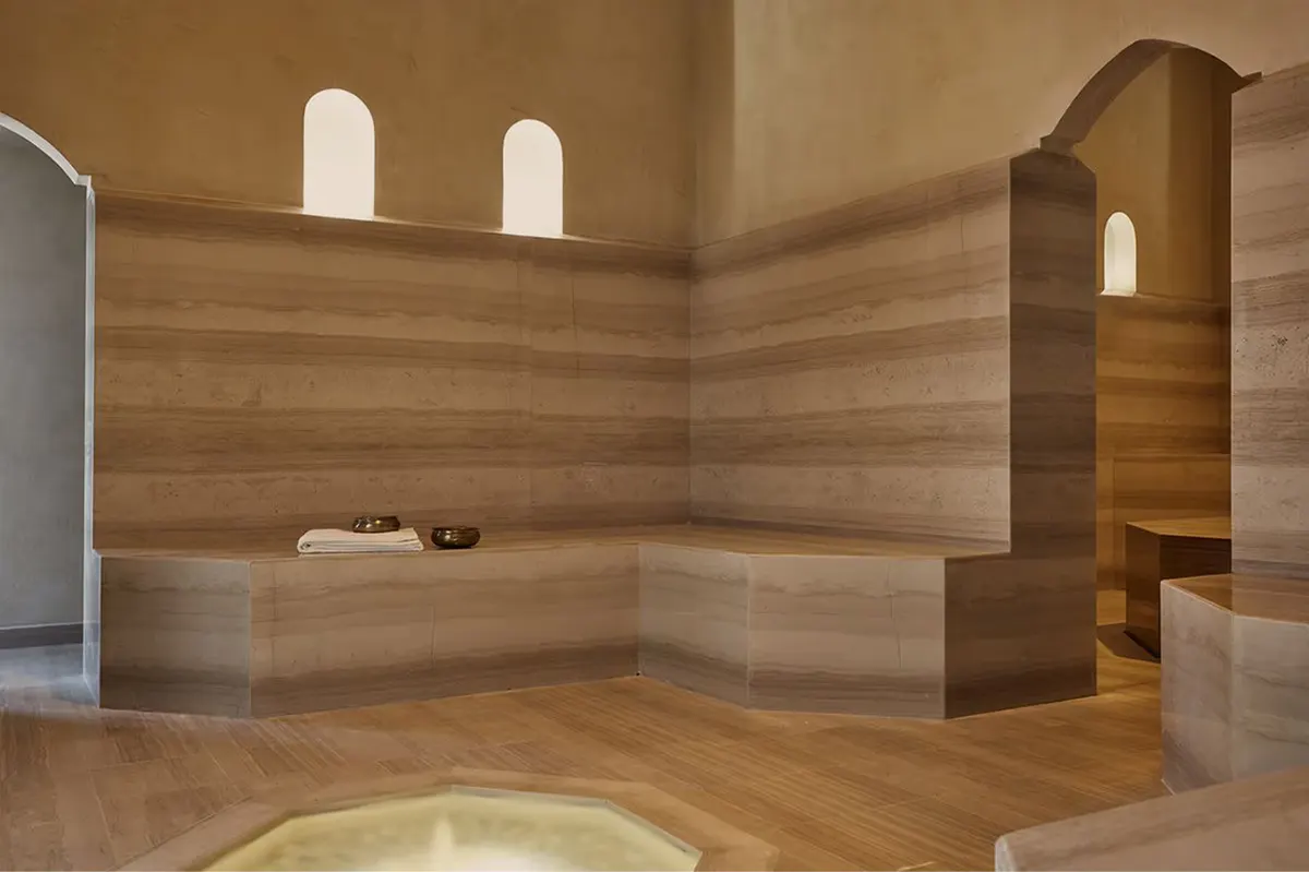 A modern spa room with pale wood paneling, arched alcoves, and soft recessed lighting