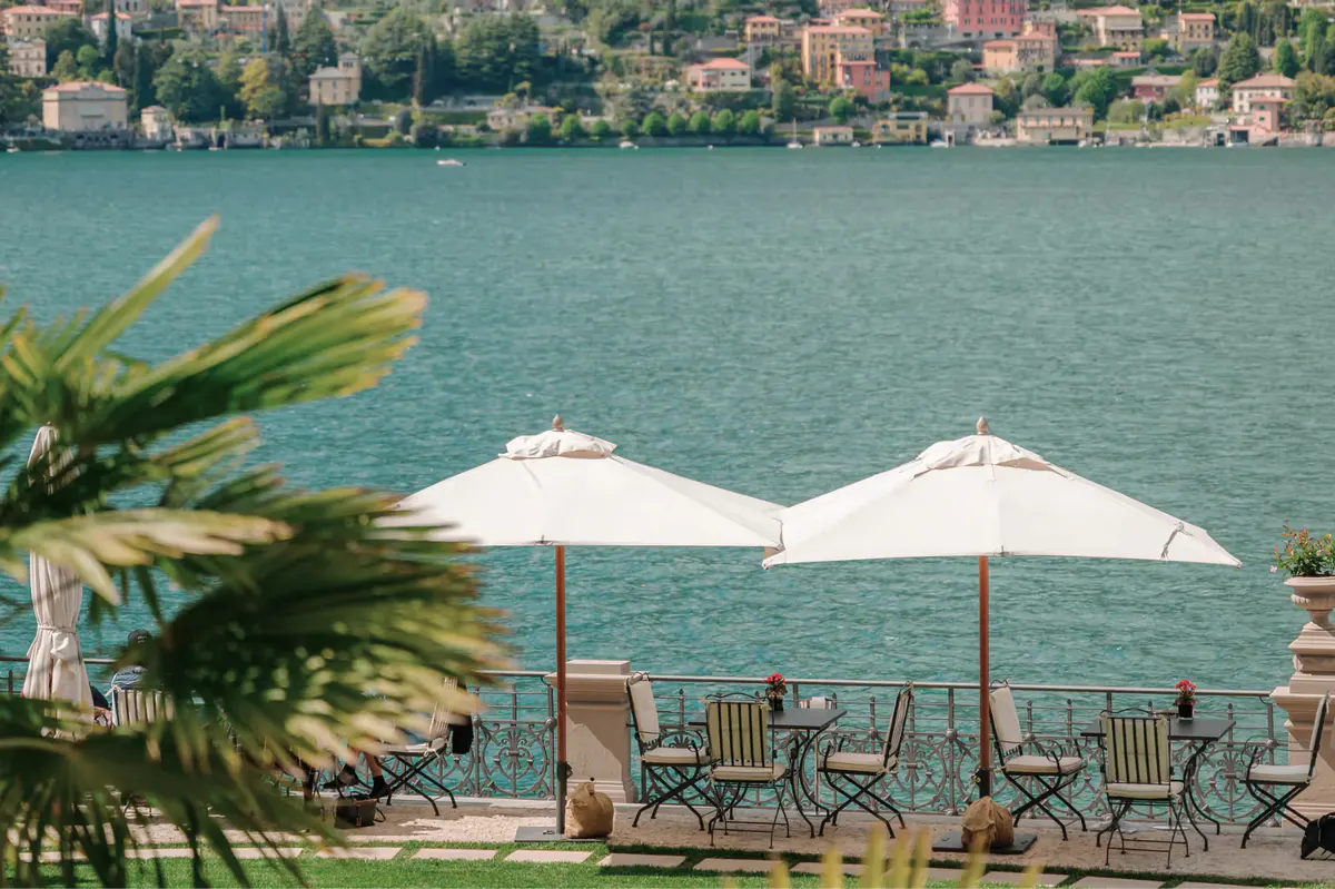 Waterfront dining with white umbrellas, wooden chairs, and turquoise lake water