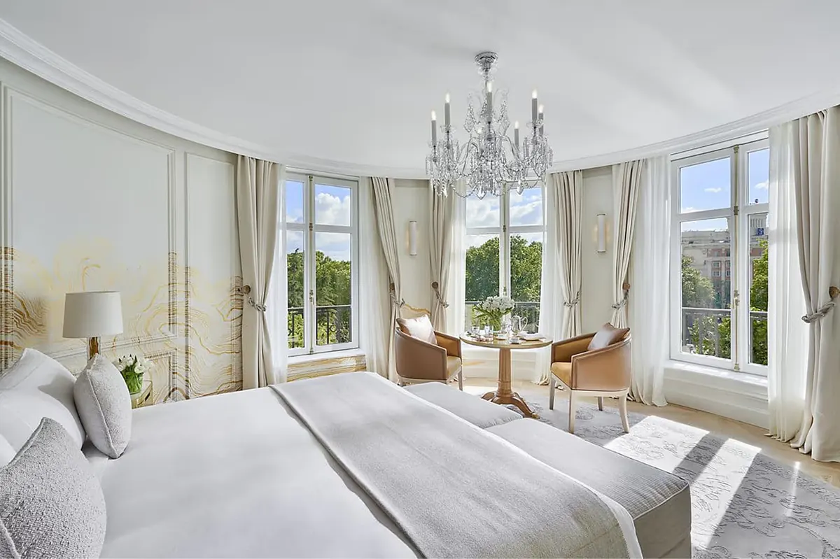 Bedroom with white bedding, tall windows, and brass table lamps