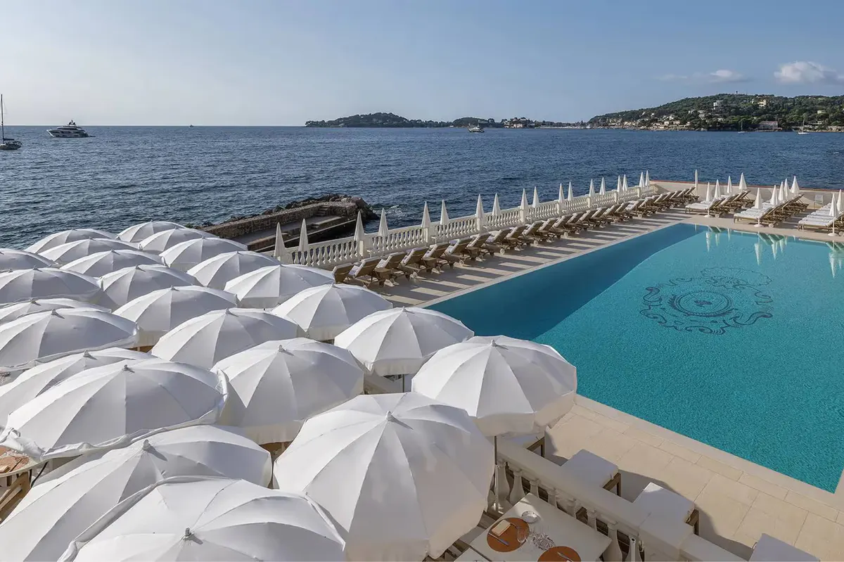 Pool deck with white umbrellas and sea horizon in the distance