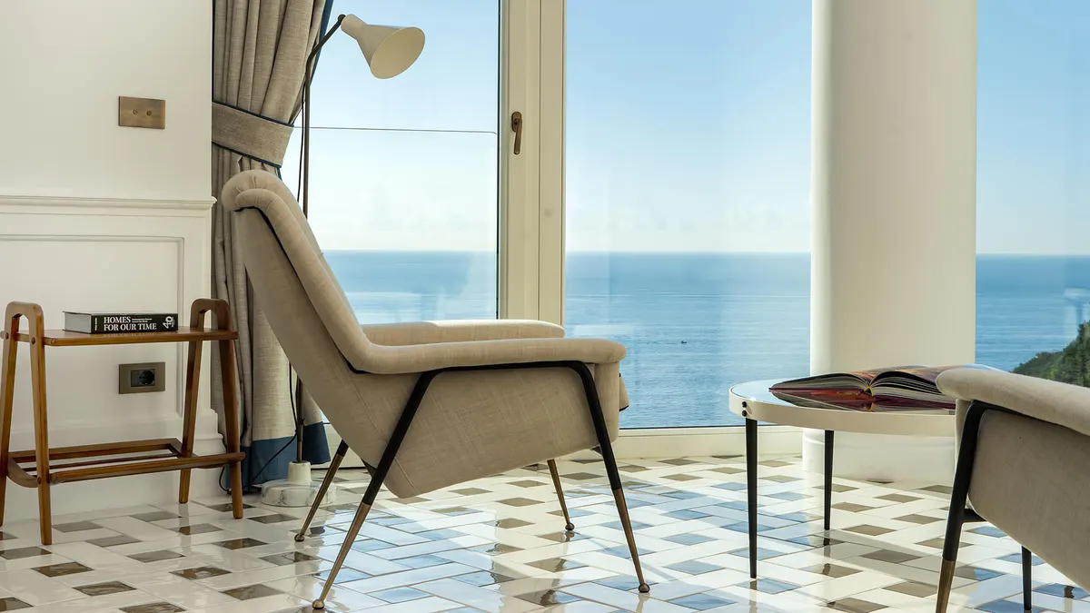 Minimalist seating area with modern chair overlooking seascape through floor-to-ceiling windows