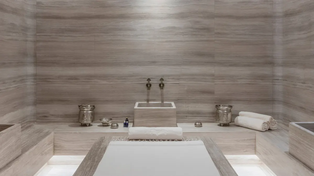 A spa treatment room with rectangular sunken tub and minimal stone finishes
