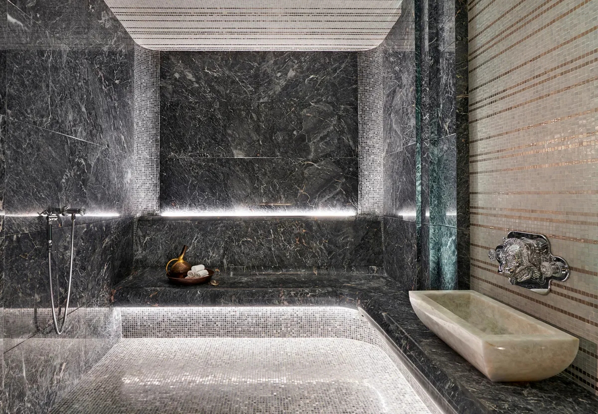 A spa bathroom with dark marble walls, a deep soaking tub, and natural light