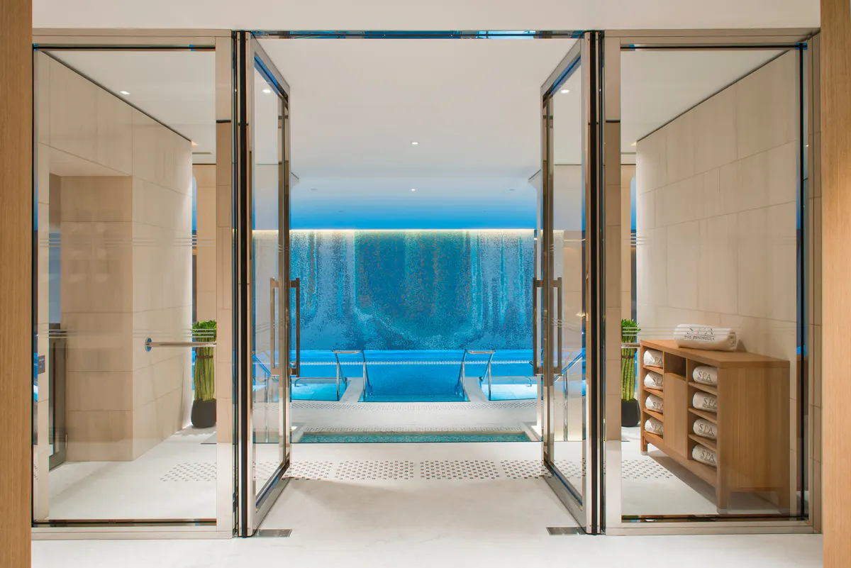 Indoor swimming pool with curved ceiling, blue water, and overhead lighting in a spa setting