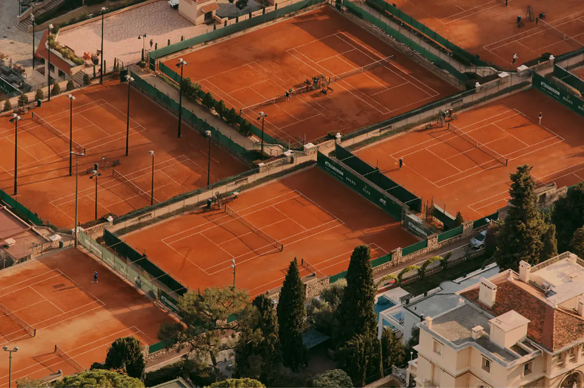 Clay tennis courts on hillside overlooking coast