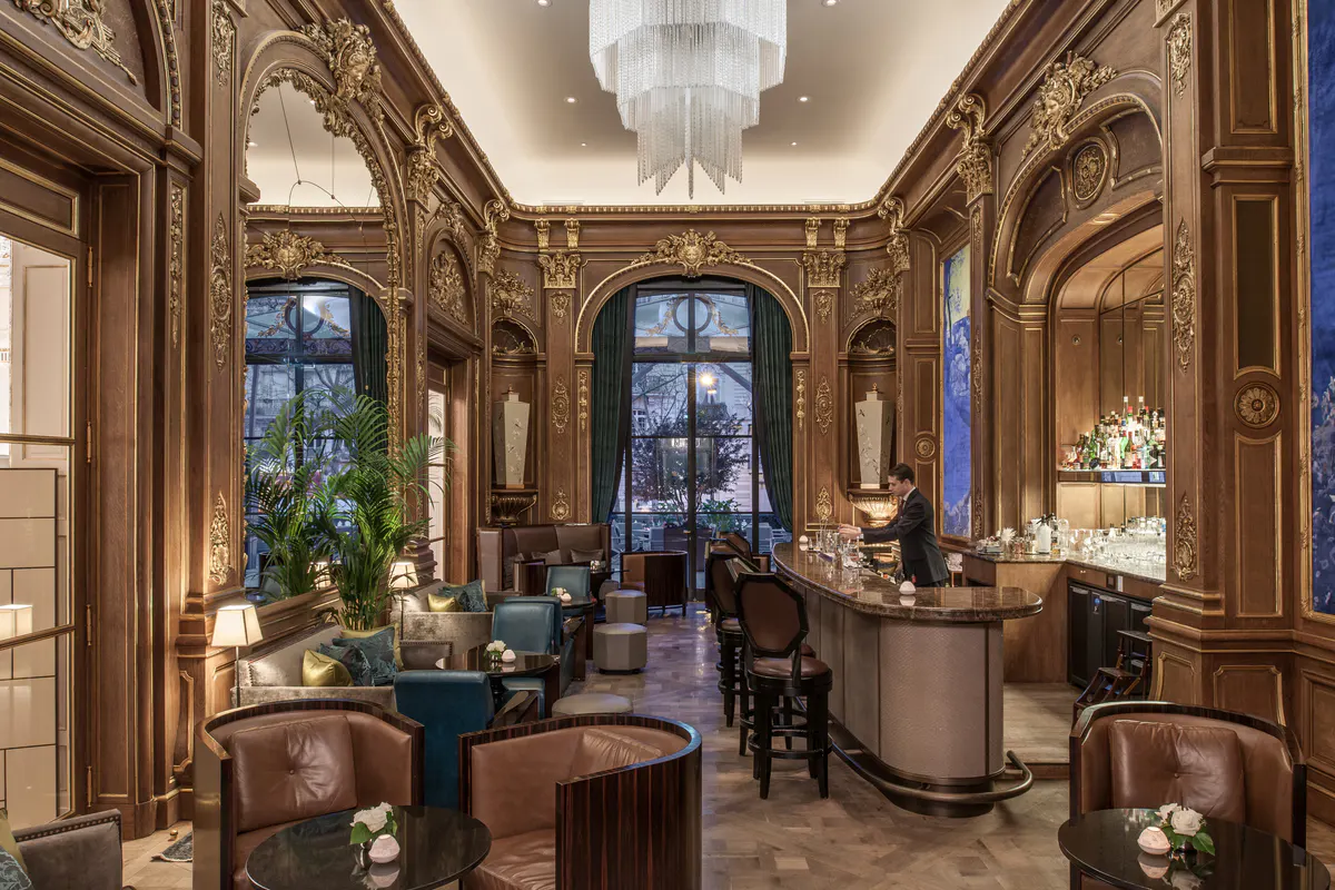Ornate lounge with wood paneling, blue velvet seating, arched ceilings, and classical fixtures