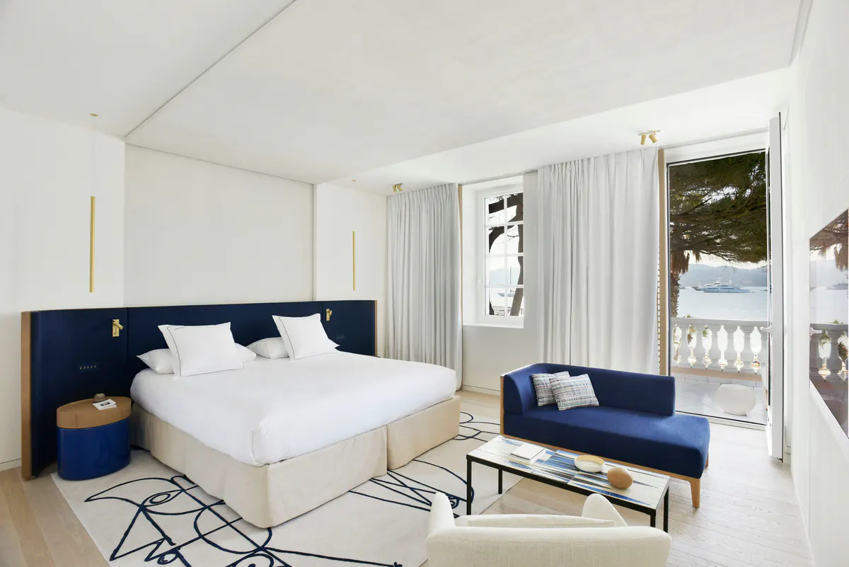 Contemporary bedroom with navy headboard and sea-view terrace