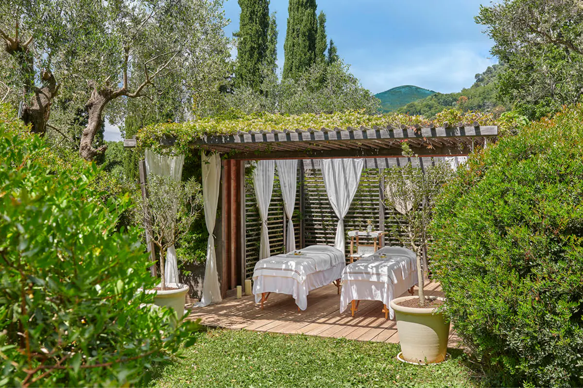 Garden cabana with pergola and lounge area near cypress-lined path