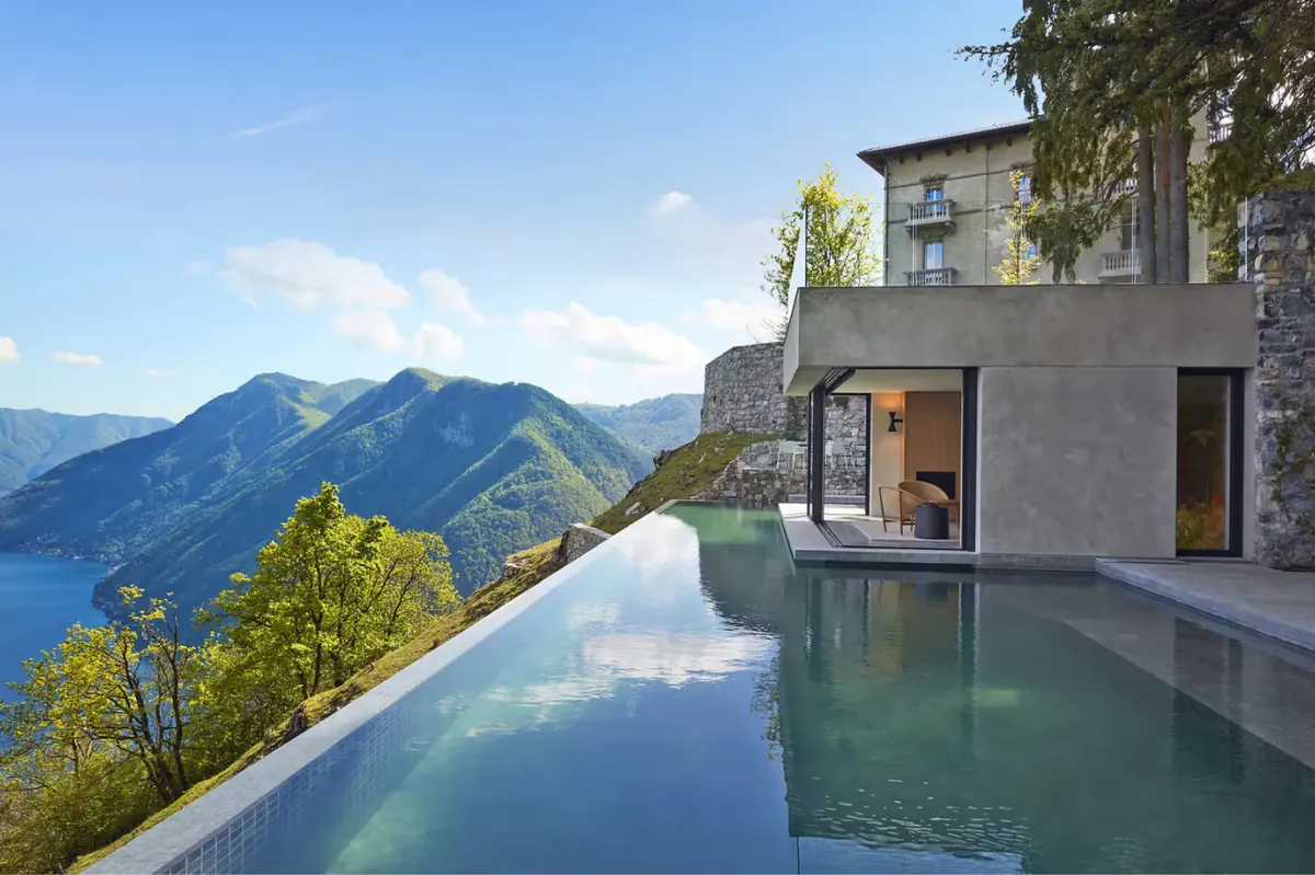 A terraced infinity pool overlooking Lake Como and surrounding mountains under clear skies