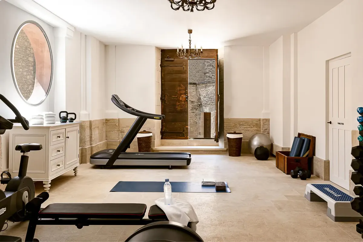 A bright gymnasium with exercise equipment, fitness machines, and a large window for natural light