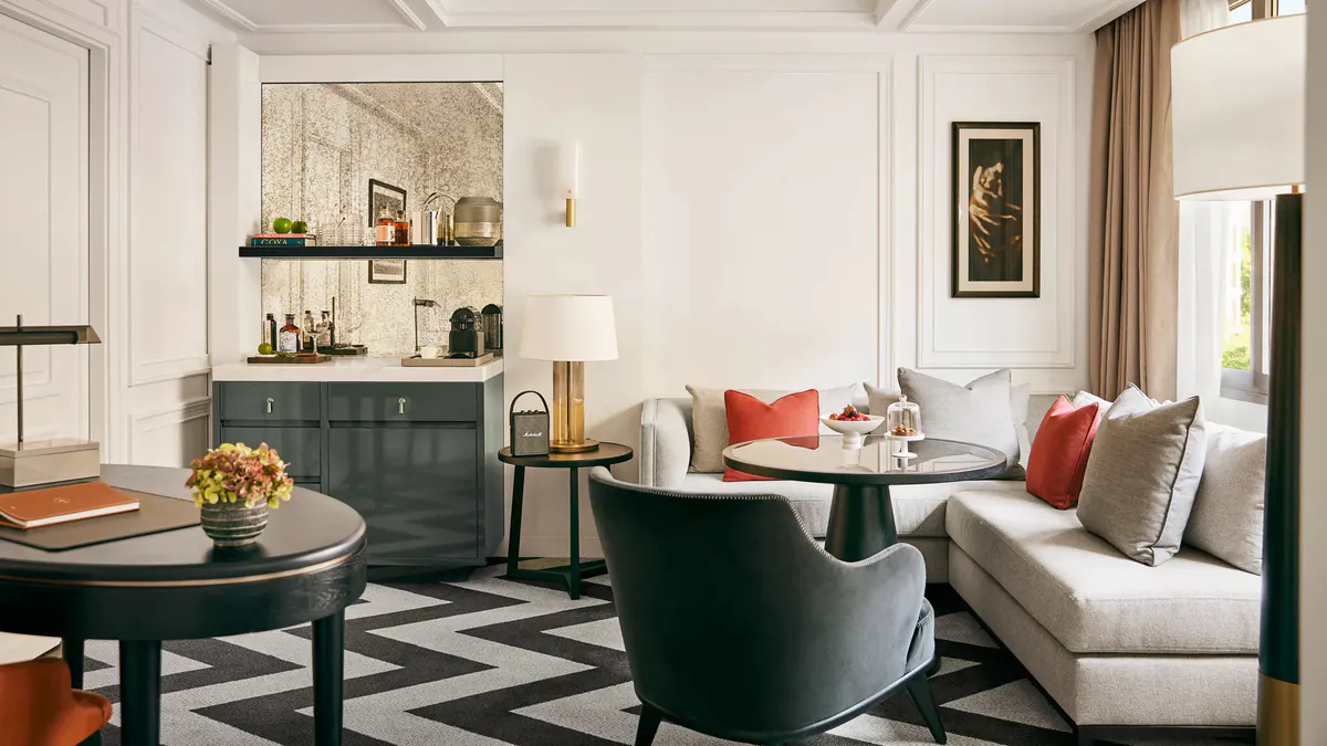 A living room with teal accent chair, neutral sofa, and dark wood furnishings with gold accents