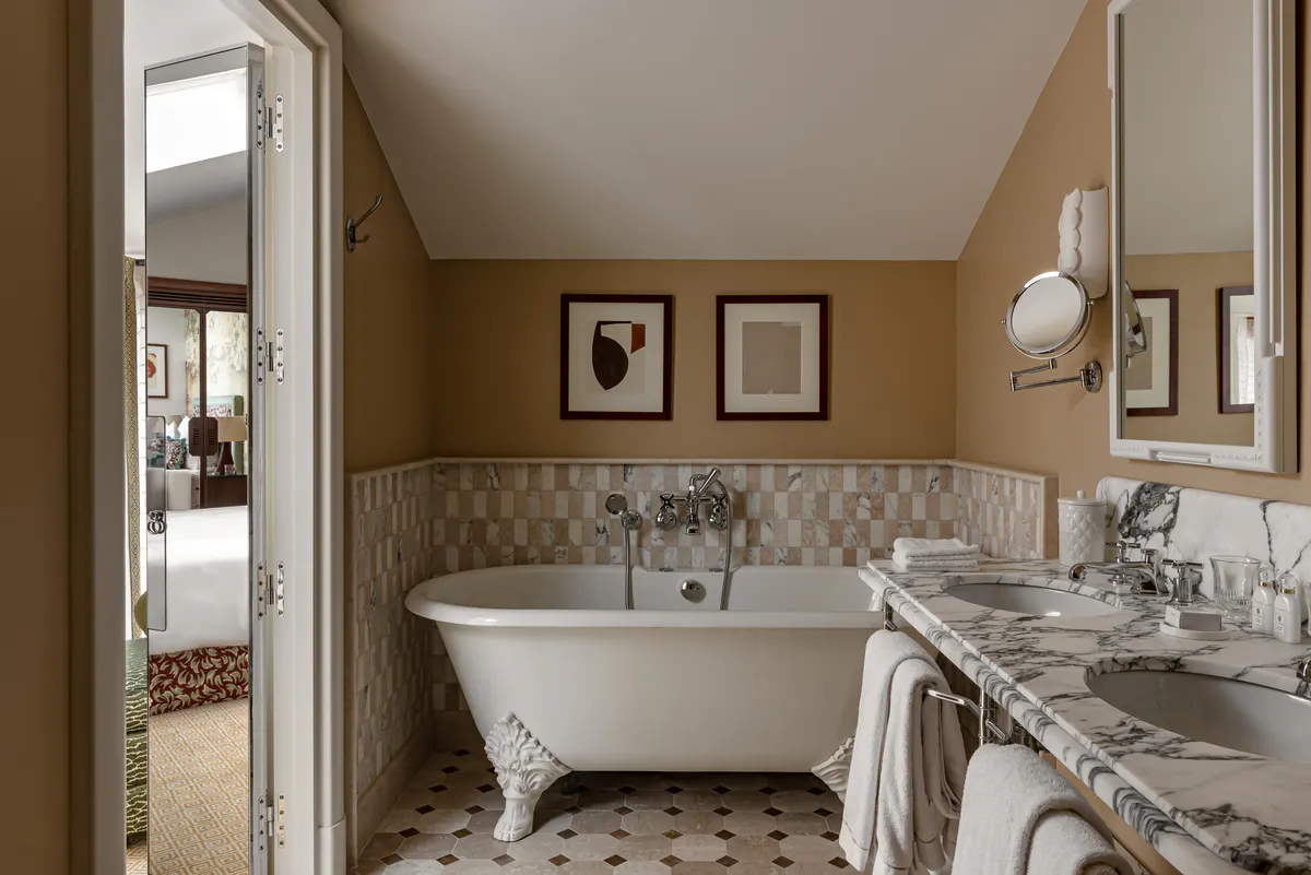Spa bathroom with white free-standing tub, marble details, and window overlooking garden