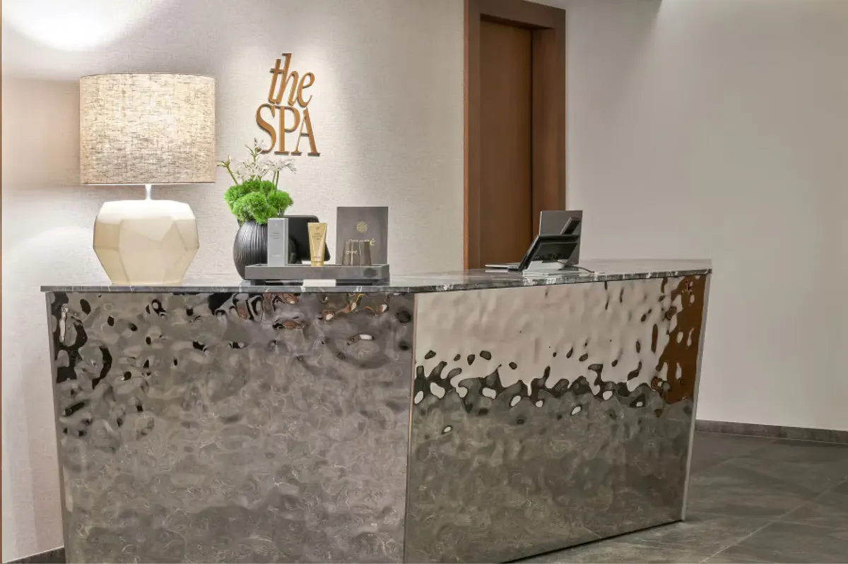 Modern reception desk with concrete finish and subtle lighting in neutral lobby space