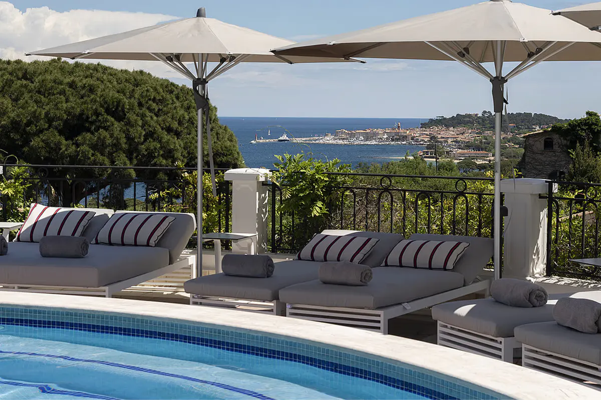 Shaded lounge terrace with striped cushions overlooking the bay