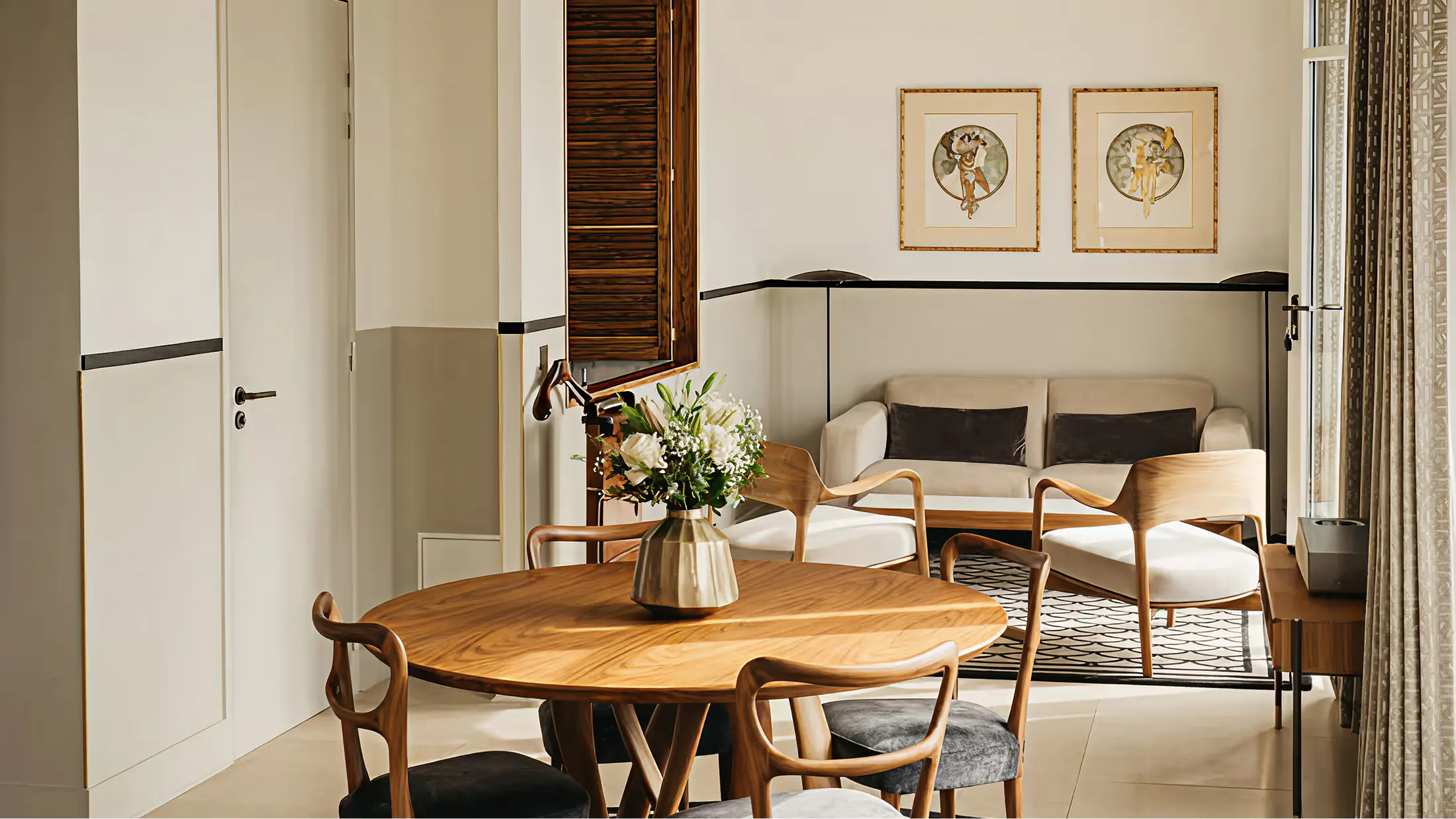 A minimalist dining room with wood table, woven chairs, and framed botanical prints