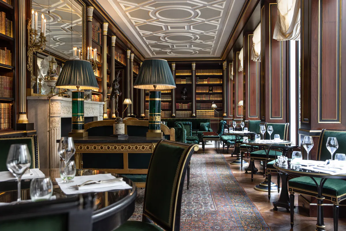 The dining room with black leather banquettes, gilded paneling, and jewel-toned furnishings