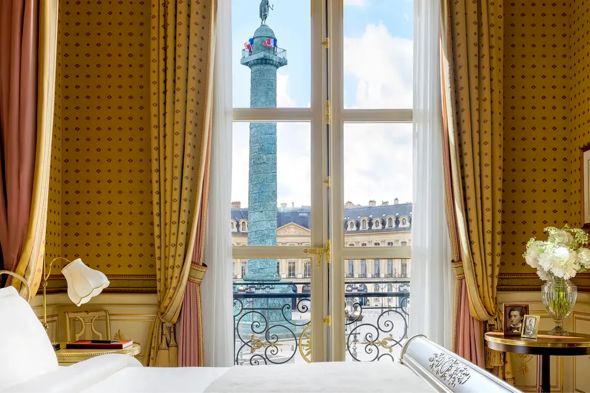 A room window framing the Vendôme Column with golden curtains and cream furnishings